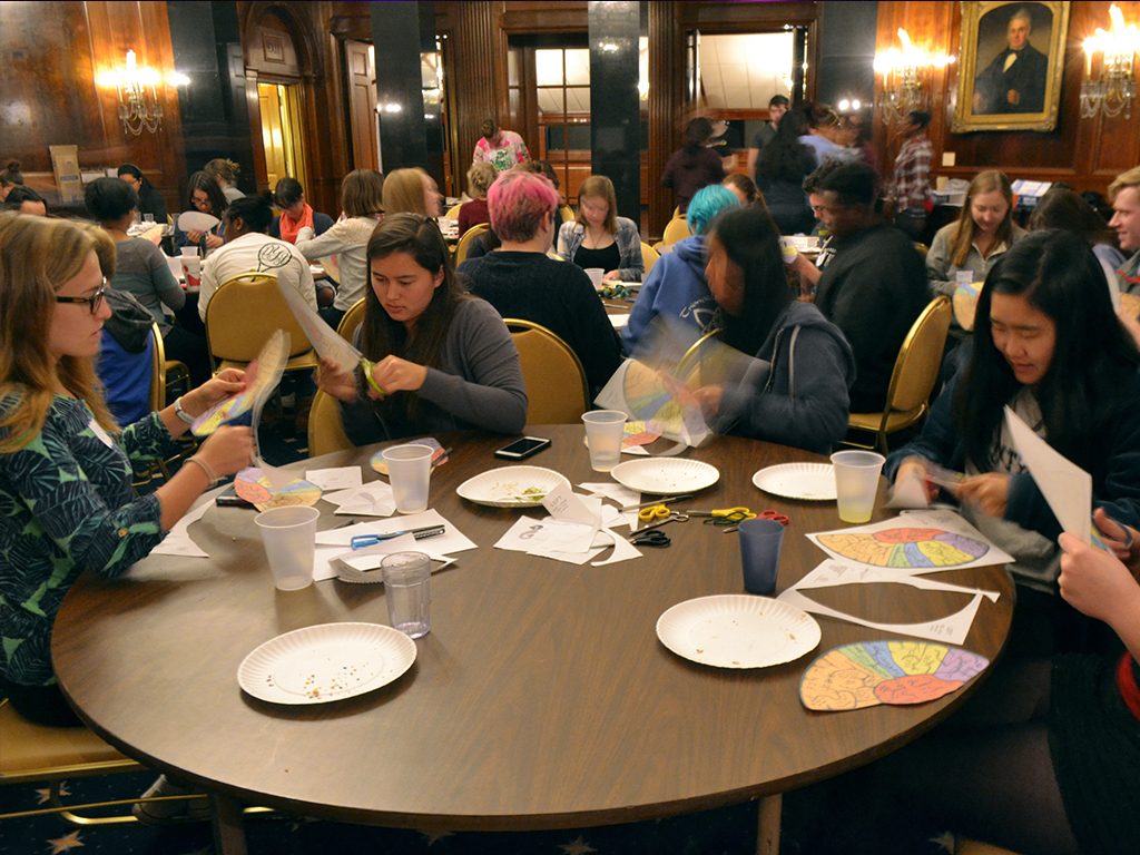 Teens around a table cut paper brains as part of a Teen Science Cafe