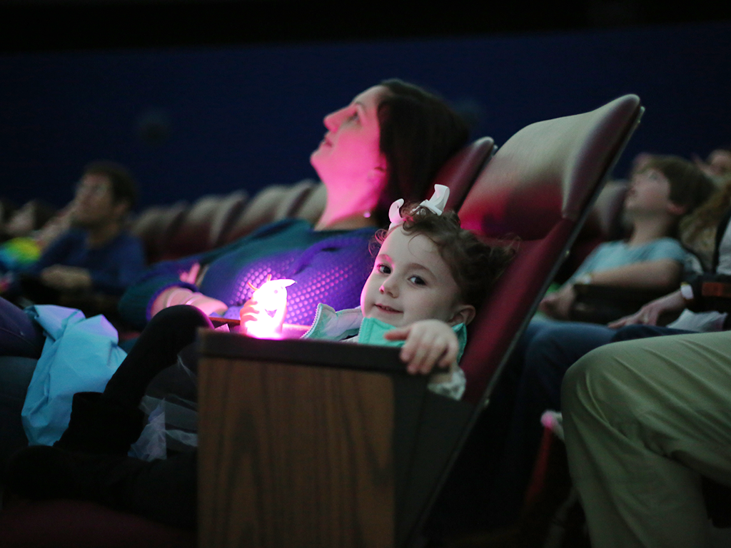 Child enjoying planetarium show in theater with parent