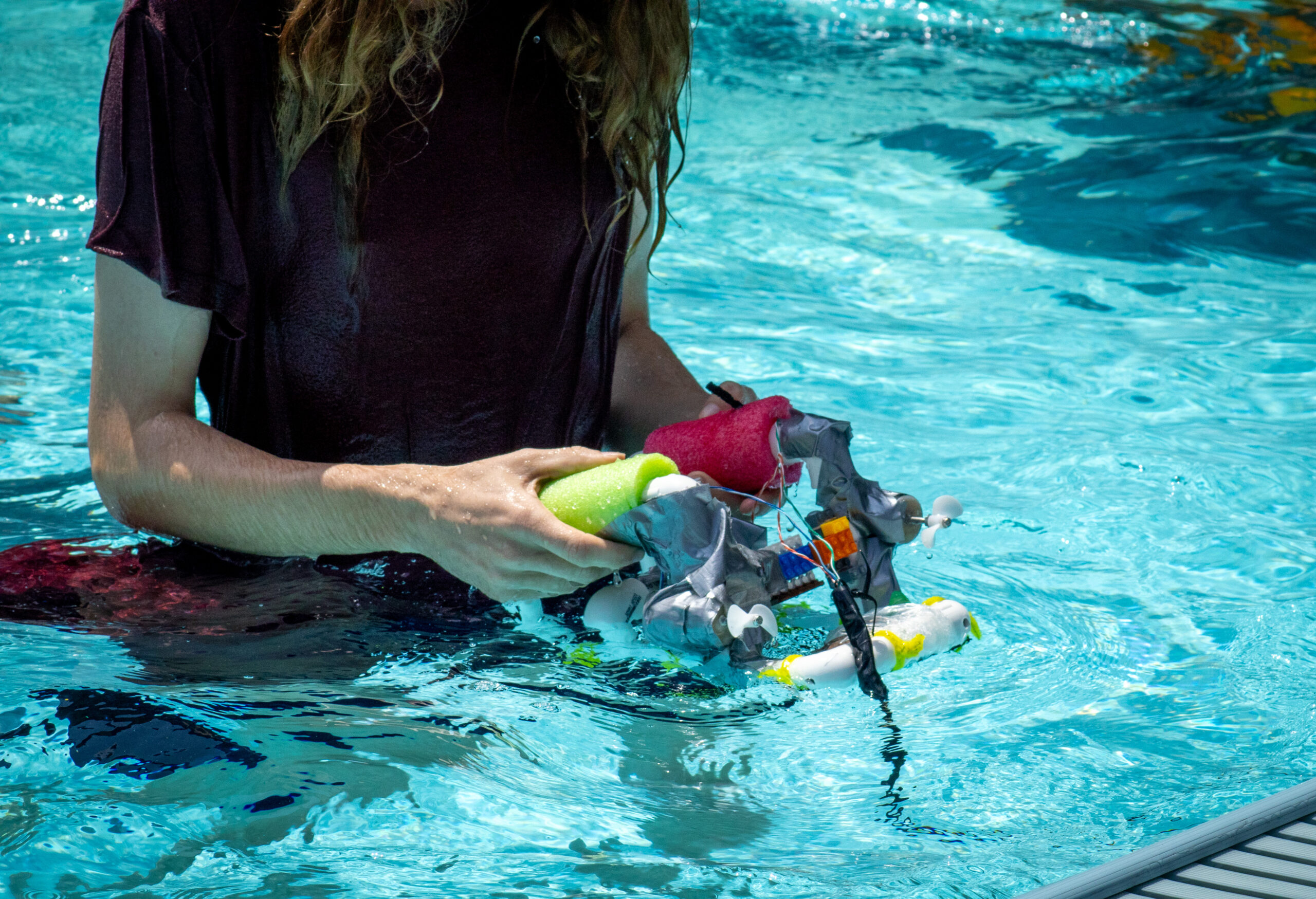 A person holds a handmade rover in a pool.