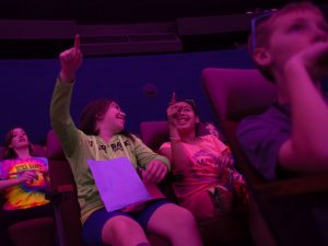 A group of students point up at the fulldome theater at Morehead Planetarium and Science Center