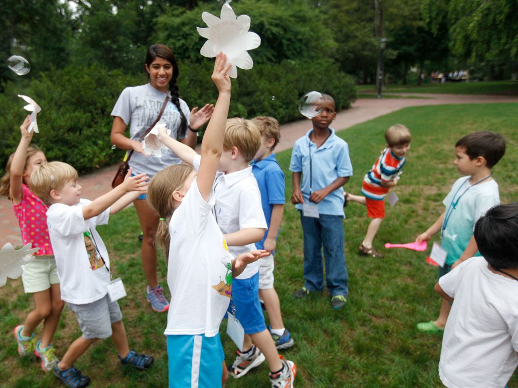 Kids play outside with paper fans and bubbles