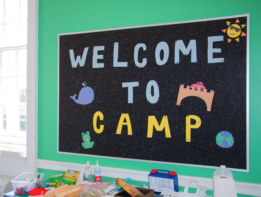 A board says, "Welcome to camp."