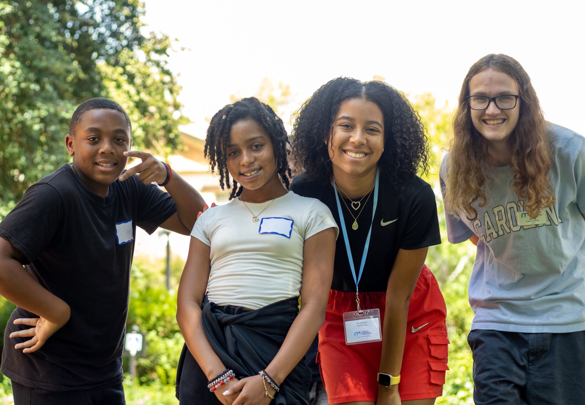 Two campers and two counselors smile and pose together.