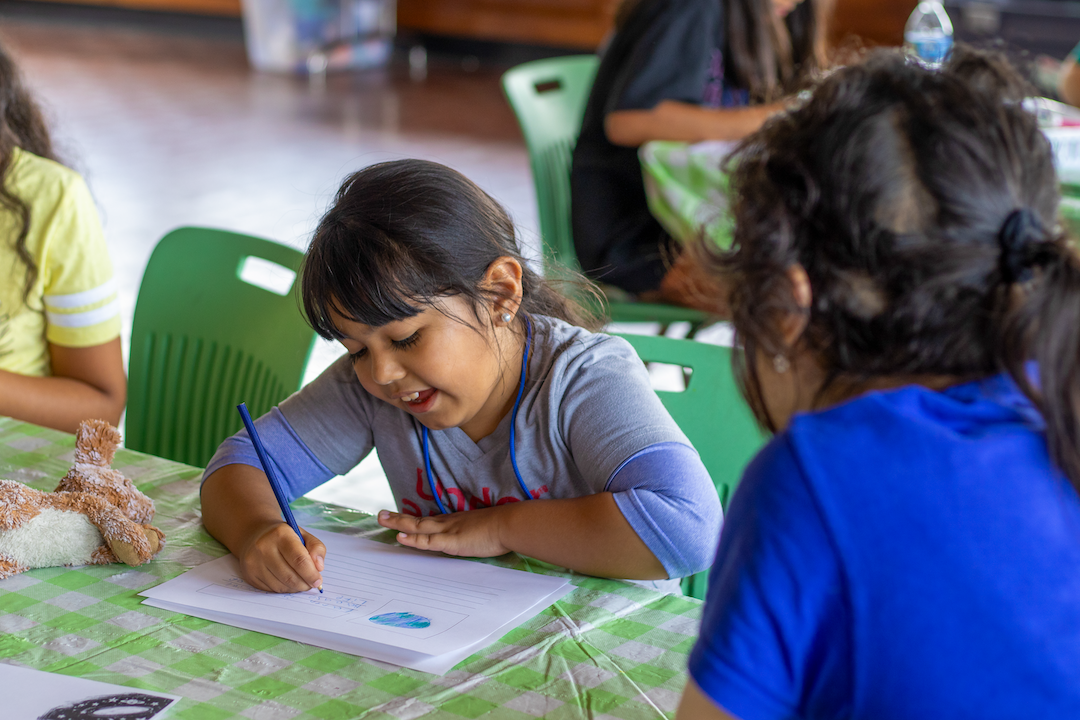 A campers smile while writing.