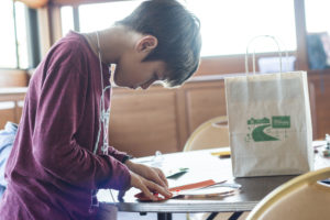 Student drawing at a table