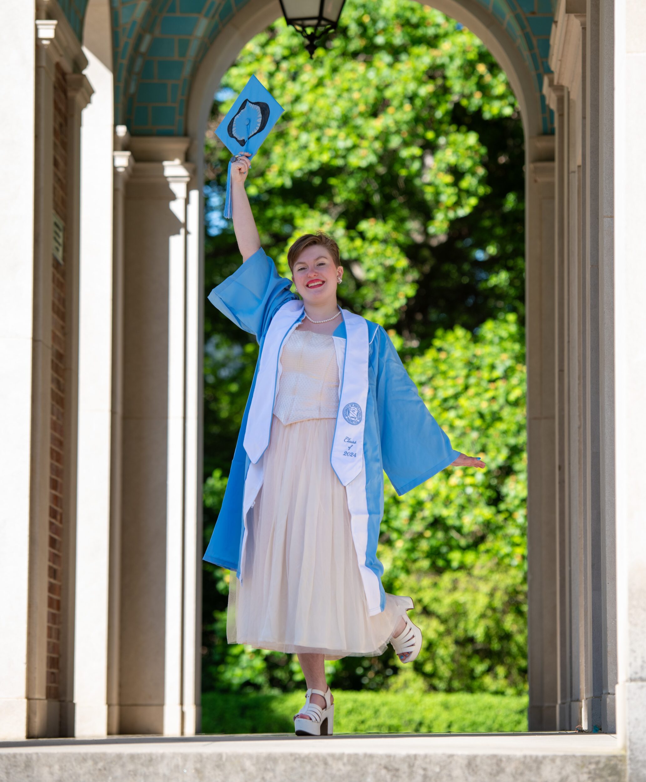 Noelle Keister wears a grad cap and gown at the UNC-Chapel Hill Bell Tower.