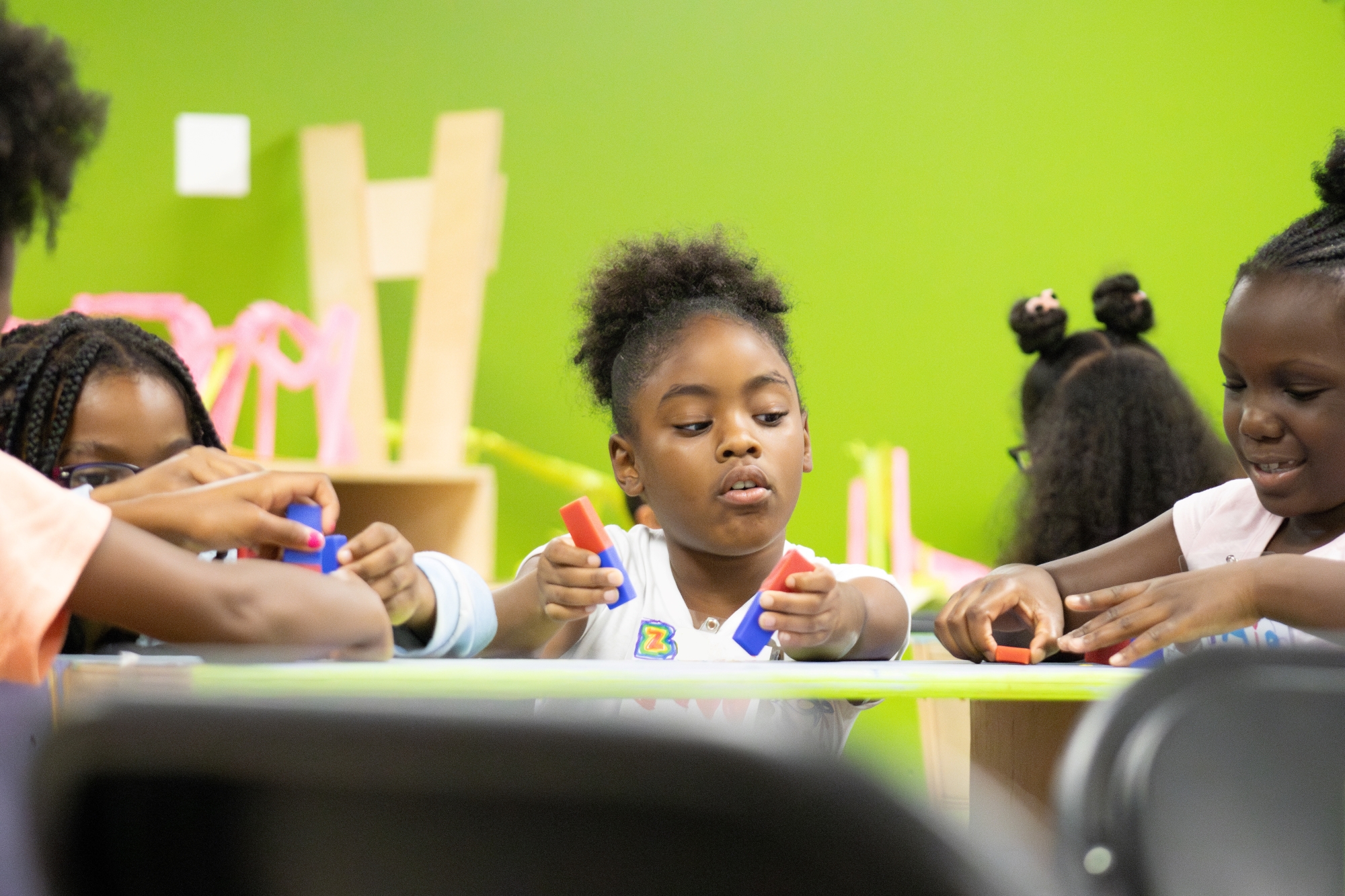 Children sit at a table using magnets to pick up different items.