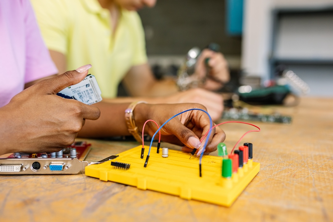 Close-up of hands creating electronic circuits and robotics.