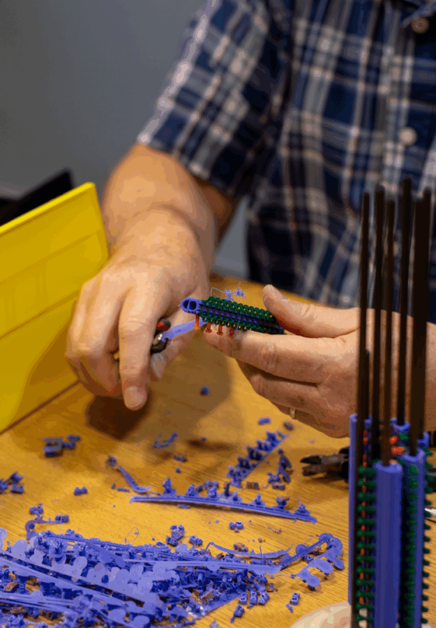 A pair of hands clip pieces of 3D-printed plastic.