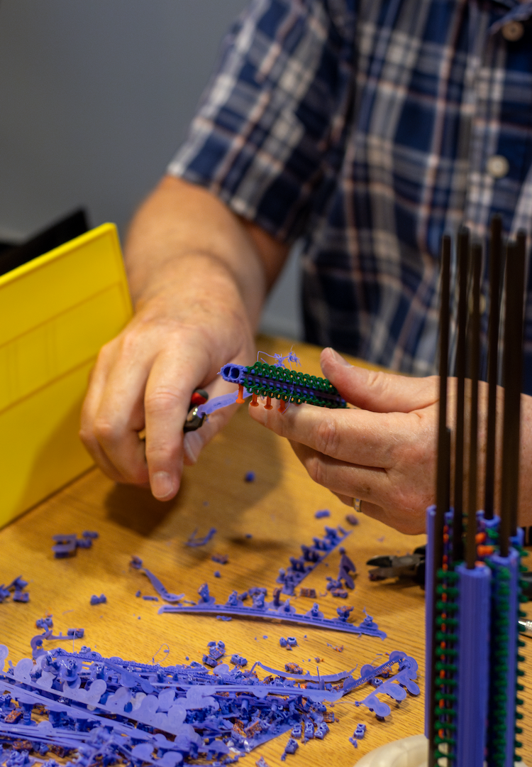 A pair of hands clip pieces of 3D-printed plastic. 