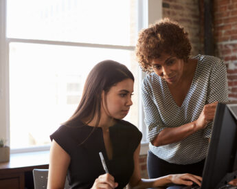 Two people work on a computer in an office.