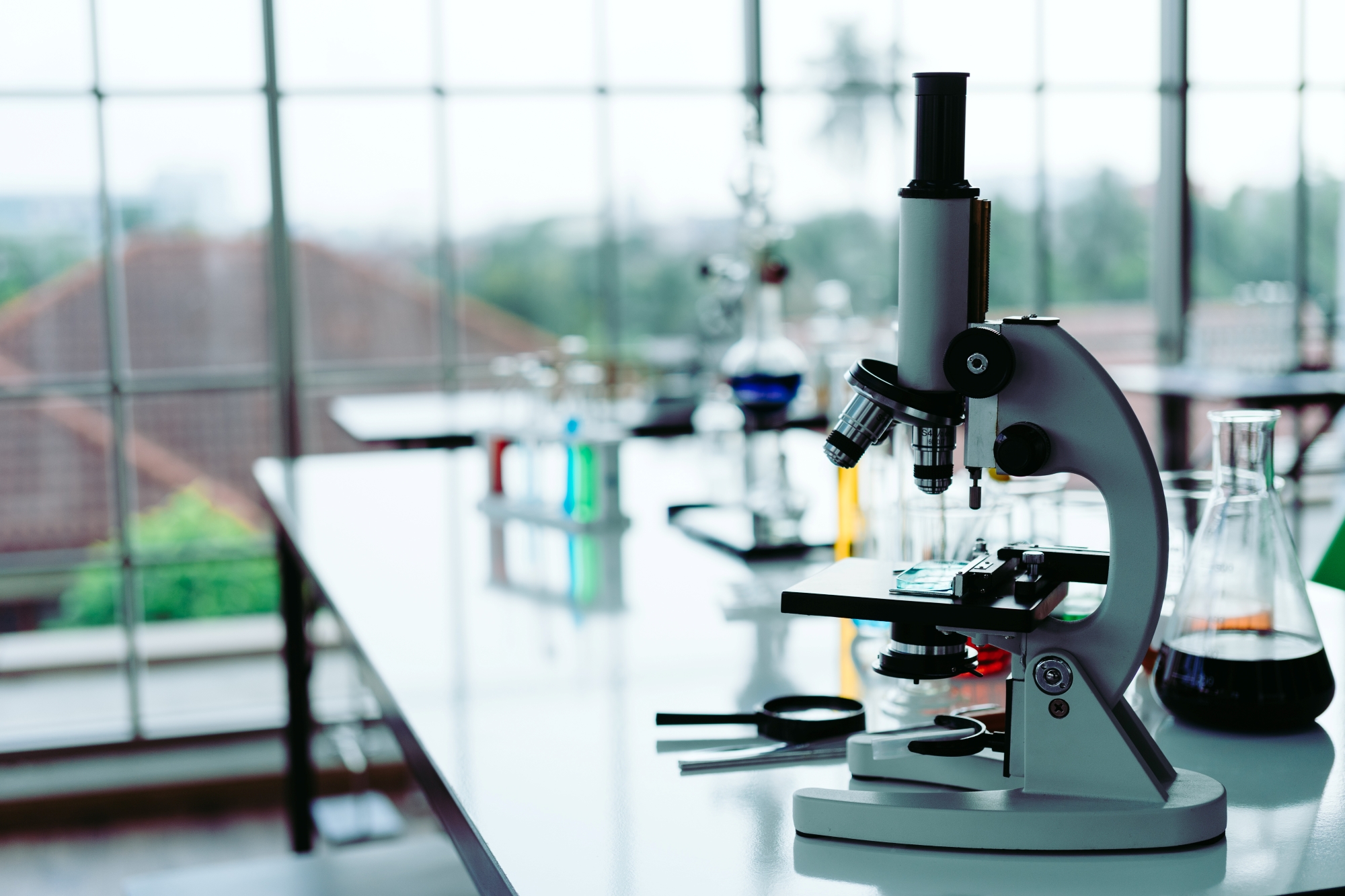 A microscope in a lab. In the background are windows looking over a landscape.