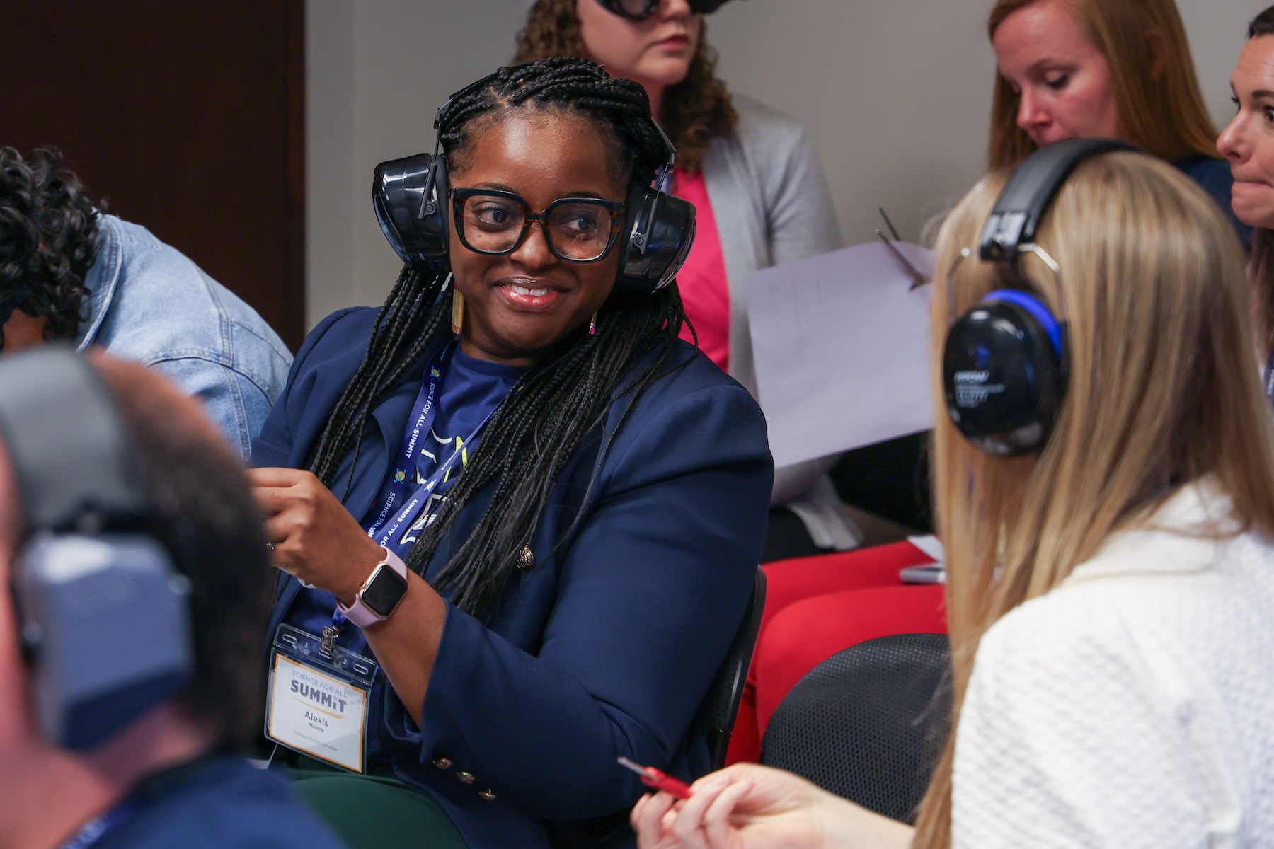 Two professionals wear noise-cancelling headphones and try to have a conversation.