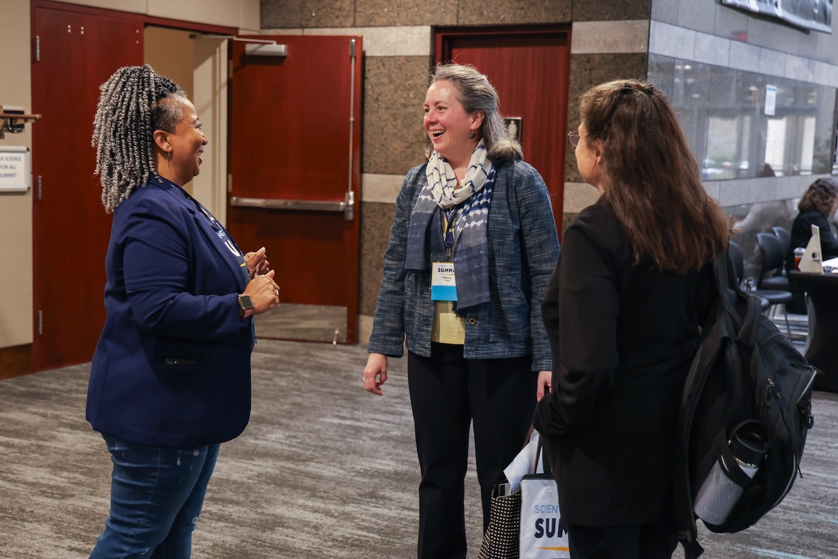 Three professionals chat at a conference. 