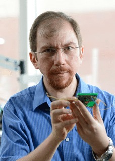 Alper Bozkurt holds a computer chip while looking at the camera.