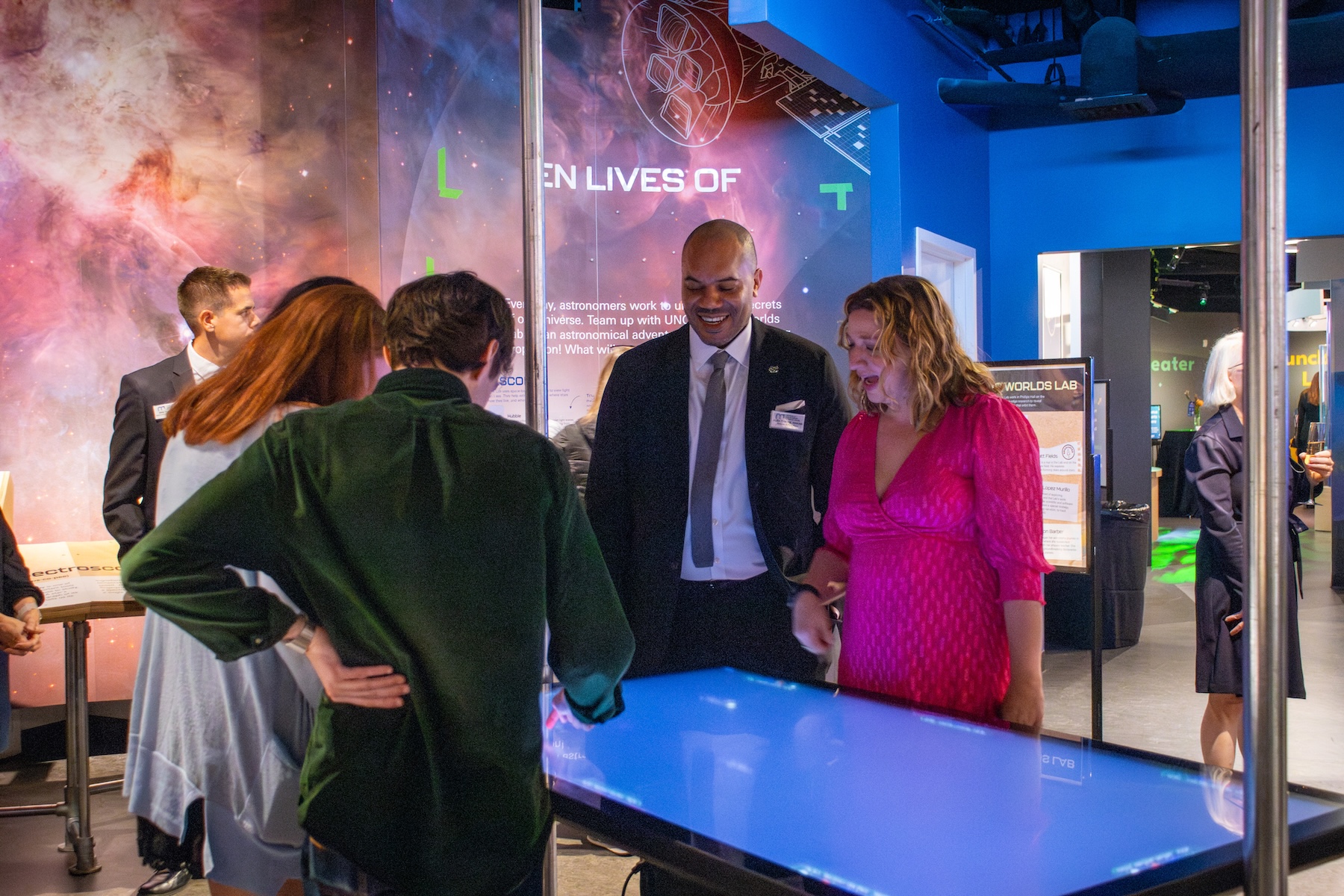 Four people stand at a touchscreen table in the upcoming Hidden Lives of Stars exhibit.
