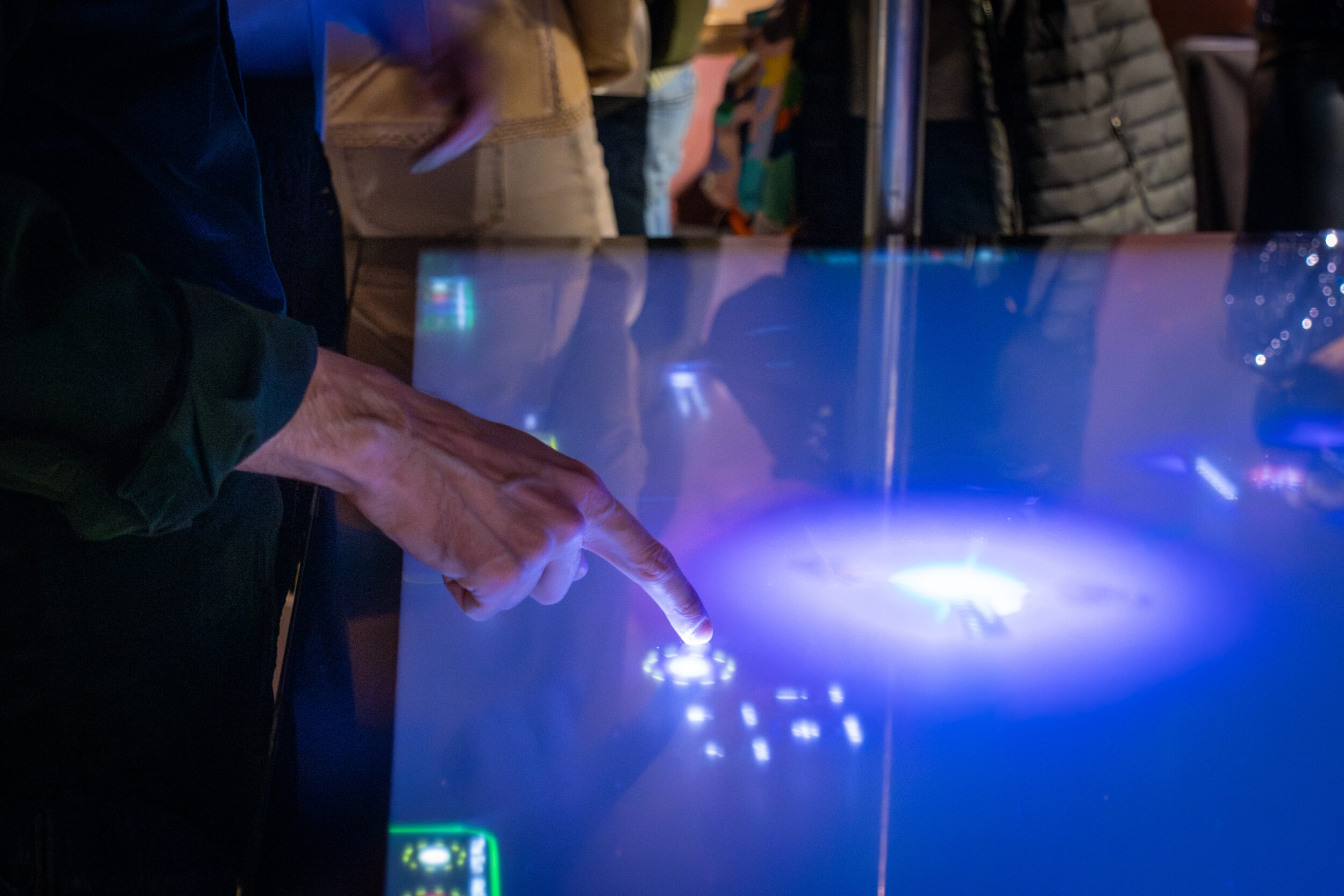 A hand touches point at a touchscreen table.