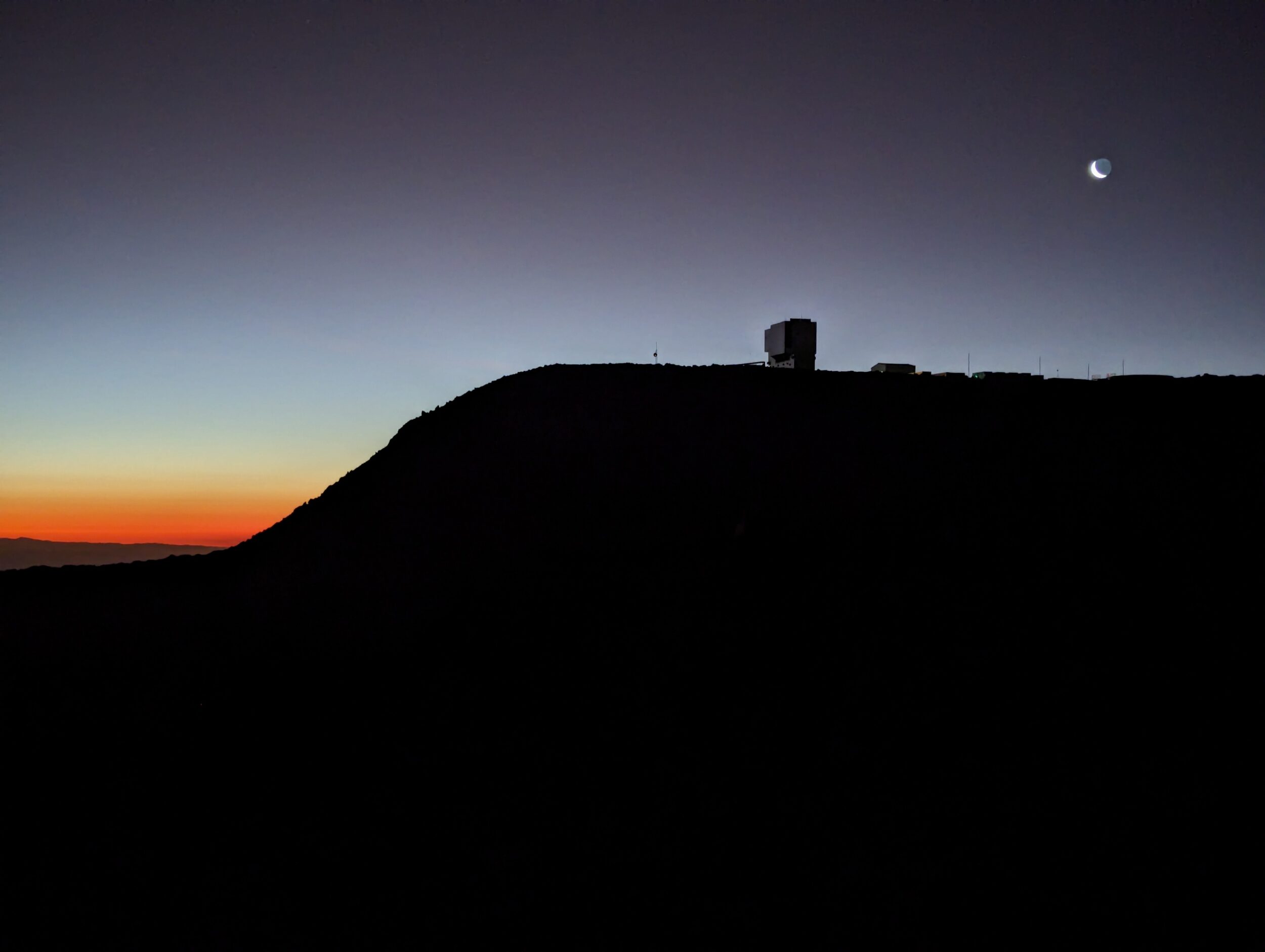 The silhouette of a large hill against a sunset.