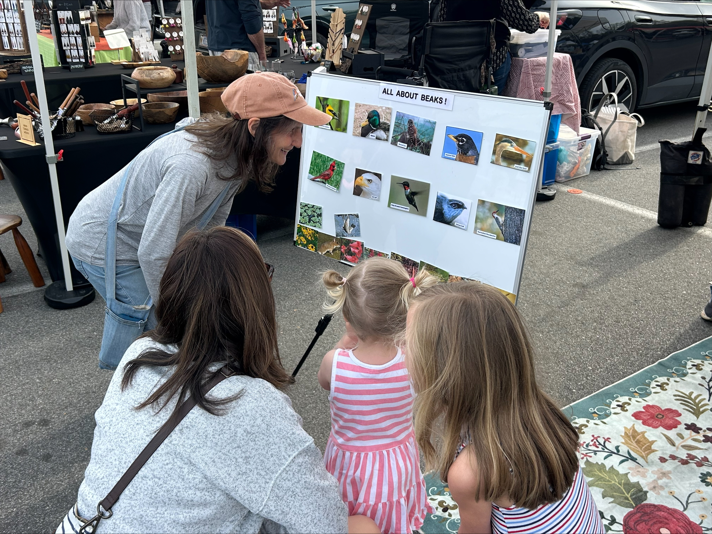 Two adults and two children kneel around a sign that says. "All about beaks!"