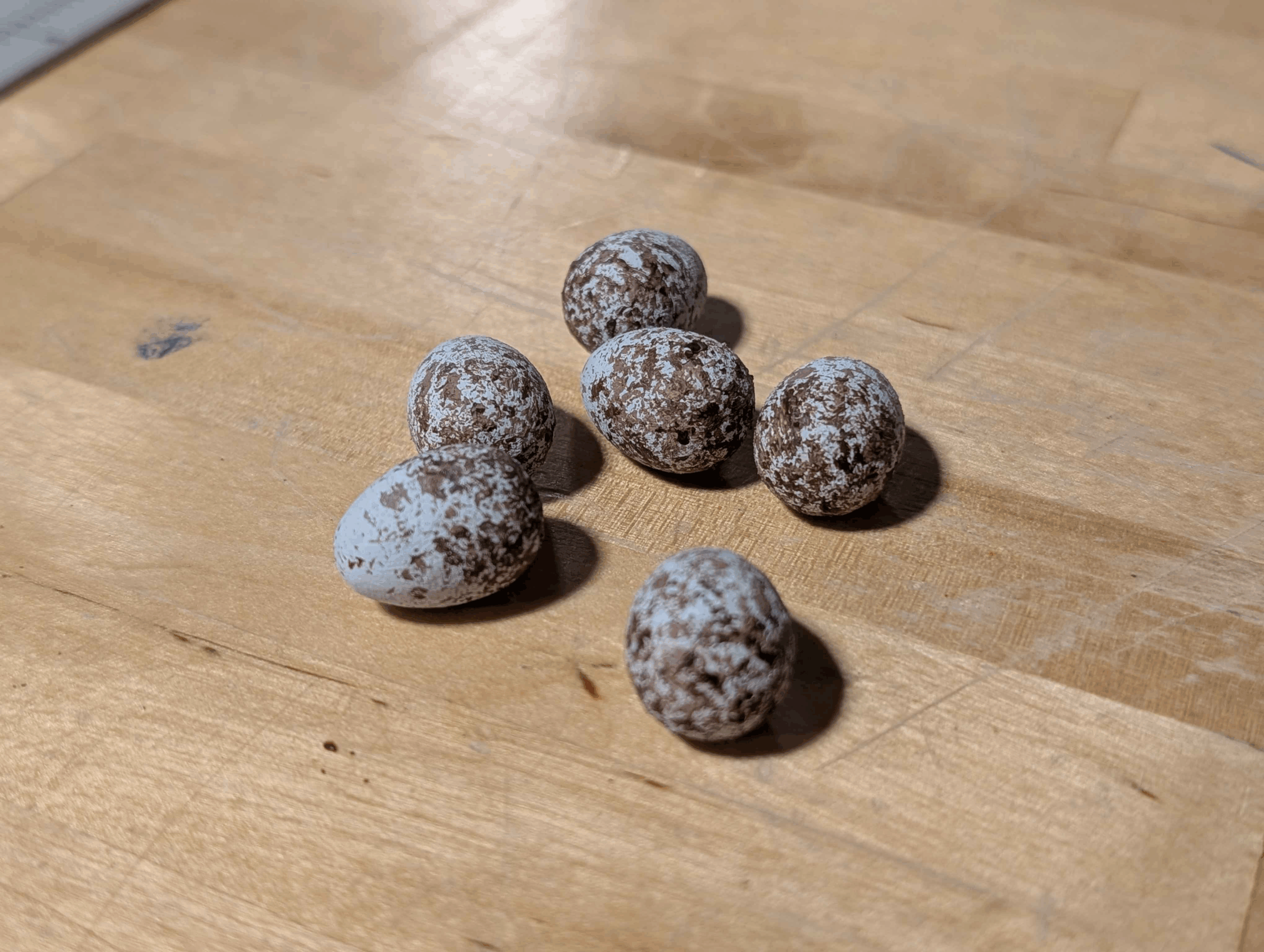 3D-printed bird eggs on a wooden surface.