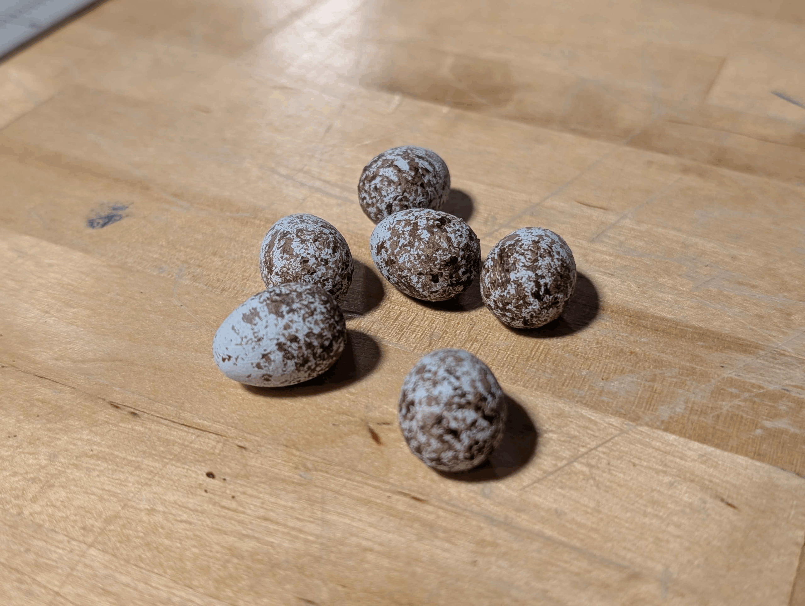 3D-printed bird eggs on a wooden surface.